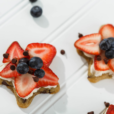 Photo of star-shaped cookies topped with sliced strawberries, blueberries and chocolate chips