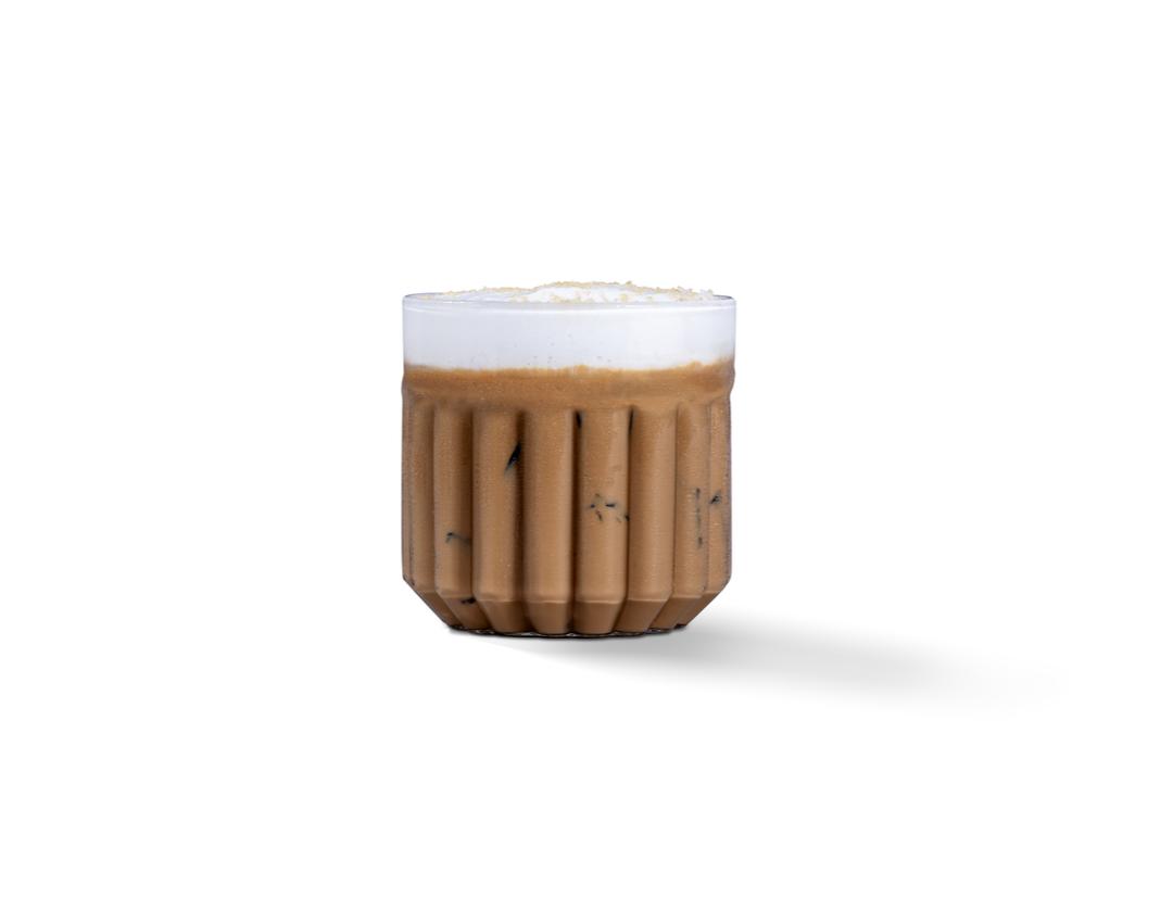 Photograph of small brown ribbed ceramic cup with frothy latte on white background and soft shadow