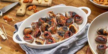 Mit Mandeln gefüllte Pflaumen im Speckmantel