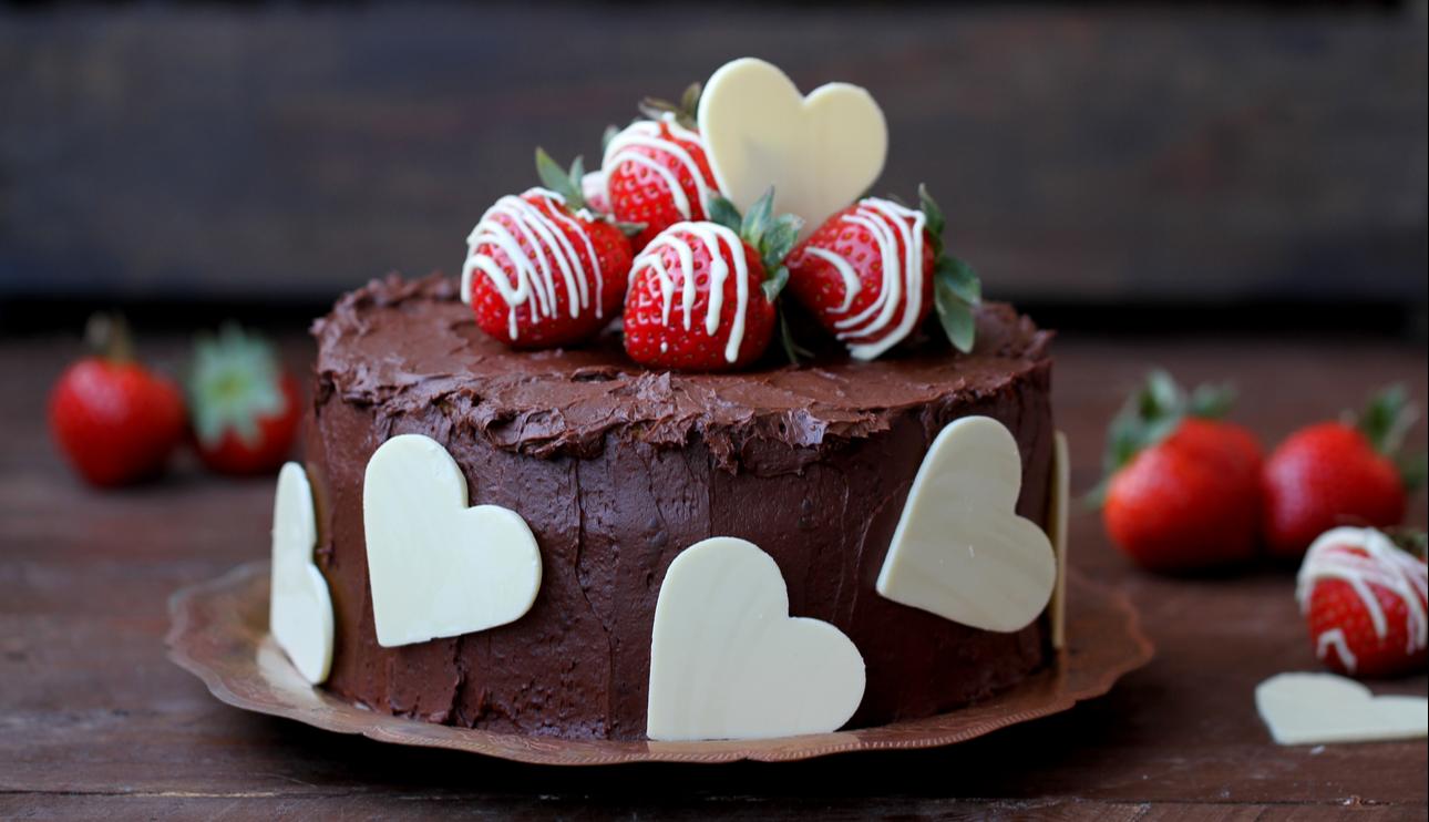 Pastel de chocolate y fresas con corazones de chocolate blanco