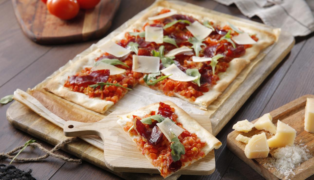 Pizza de jamón ibérico y tomate con rúcula y parmesano