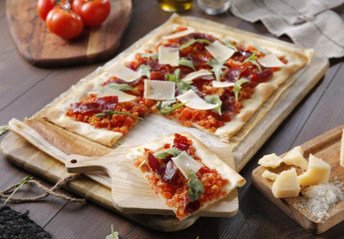 Pizza de jamón ibérico y tomate con rúcula y parmesano