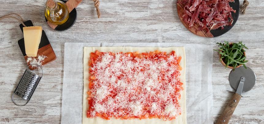 Pizza de jamón ibérico y tomate con rúcula y parmesano