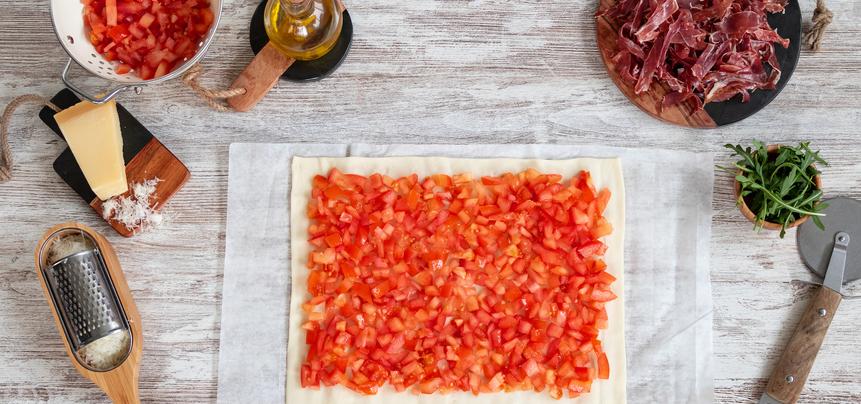 Pizza de jamón ibérico y tomate con rúcula y parmesano