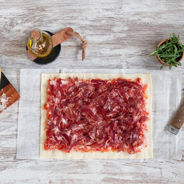 Pizza de jamón ibérico y tomate con rúcula y parmesano
