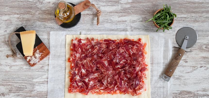 Pizza de jamón ibérico y tomate con rúcula y parmesano