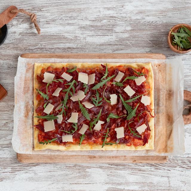 Pizza de jamón ibérico y tomate con rúcula y parmesano