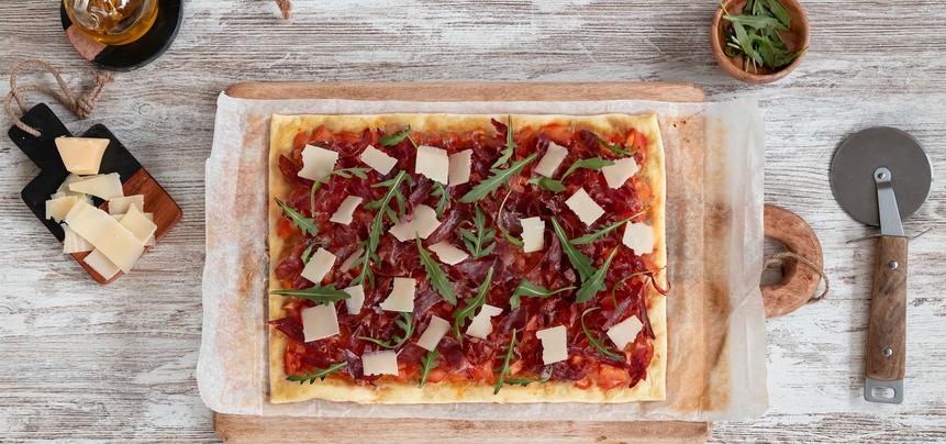 Pizza de jamón ibérico y tomate con rúcula y parmesano