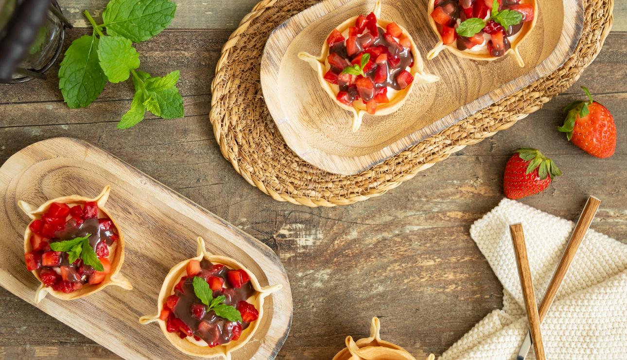 Tartaletas dulces con obleas rellenas de nata con fresas y topping de chocolate