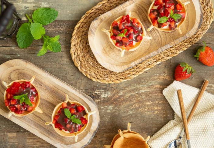 Tartaletas dulces con obleas rellenas de nata con fresas y topping de chocolate