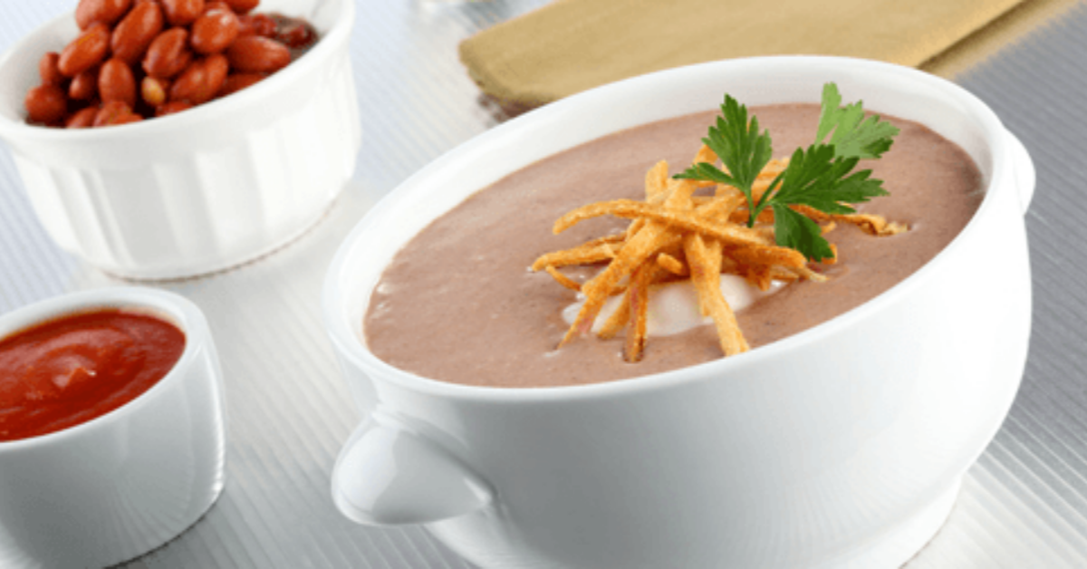 Creamy Bean Soup with NESTLÉ® Media Crema and MAGGI® Bouillon, garnished with herbs.