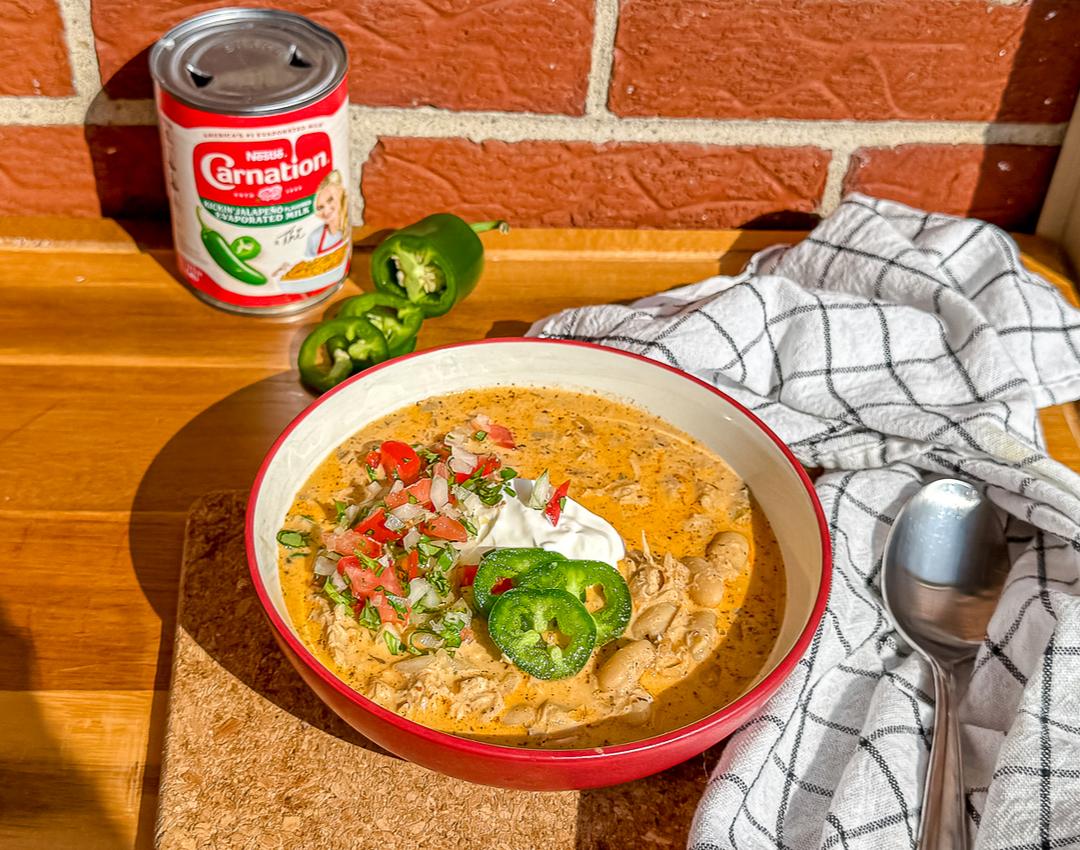 White Chicken Chili by CARNATION® MILKS with white beans, jalapeño milk, and chicken, garnished with cilantro and lime.