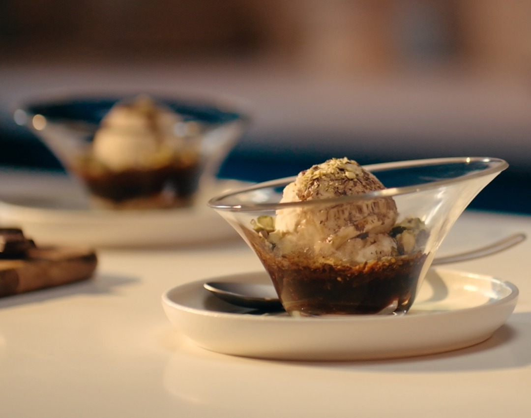 Photograph: vanilla ice cream scoop over espresso in glass bowl on white saucer.