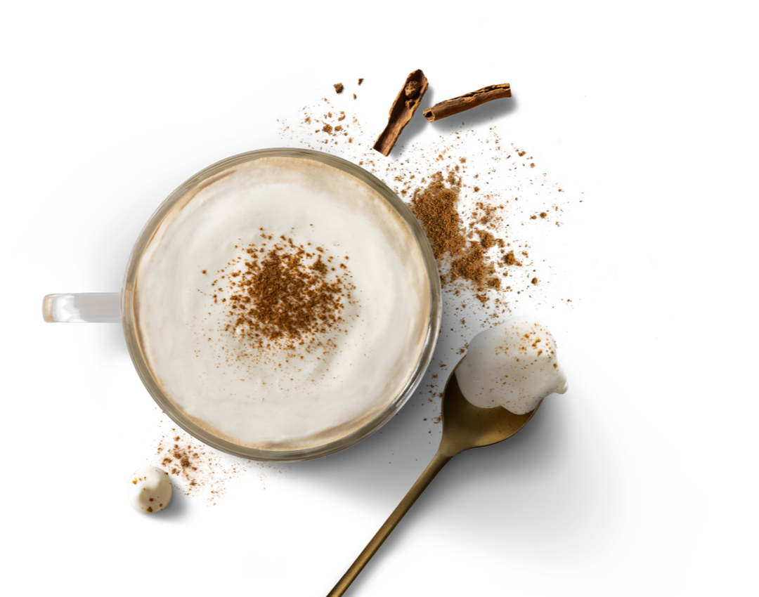 Cappuccino with cinnamon dust, gold spoon with foam, spilled cocoa and two coffee beans