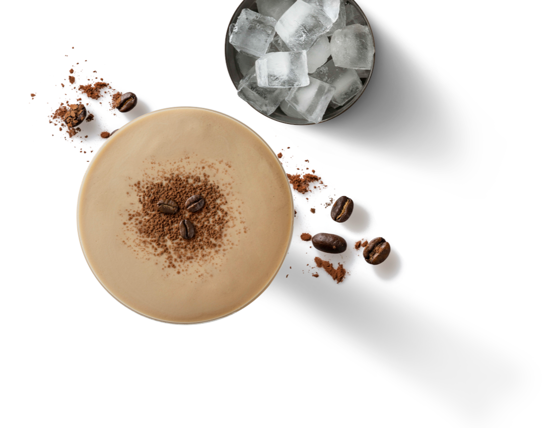 Top-down photo of iced coffee with cocoa dust, glass of ice and scattered coffee beans